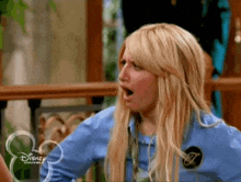 a blonde woman with her mouth open is wearing a blue shirt from disney channel