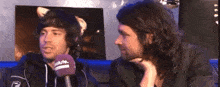 two men are talking to each other and one has a purple microphone with the word solution on it