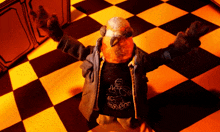 a stuffed animal wearing a shirt that says ' mr. rash ' on it is standing on a checkered floor