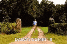 a man is walking down a dirt road with the words `` dada 's comin '' .