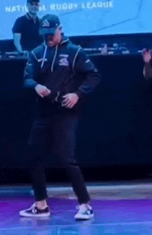 a man is dancing on a stage with the word national rugby league behind him