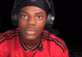 a young man wearing headphones and a red shirt .