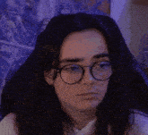 a woman wearing glasses and earrings looks at the camera
