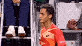 a man wearing a lotto shirt stands in front of a referee 's chair