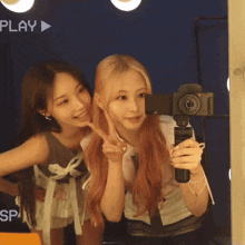 two girls are taking a selfie in front of a play sign