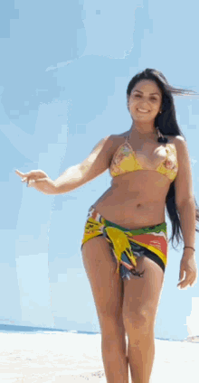 a woman in a bikini is standing on a beach and smiling