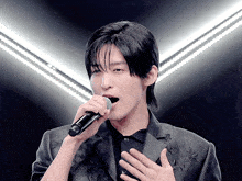a man singing into a microphone with his hand on his heart