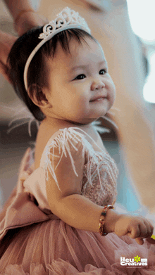 a baby wearing a tiara and a pink dress with the words you creatives on the bottom right