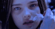 a close up of a girl holding a feather in her mouth .