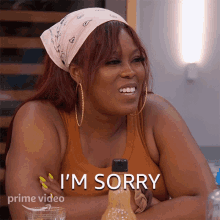 a woman with a bandana on her head says i 'm sorry in front of a bottle