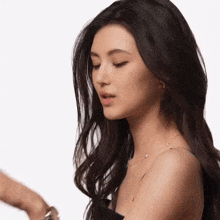 a woman with long dark hair is wearing a black strapless top
