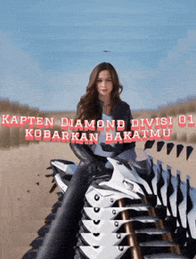 a woman is sitting on a stack of motorcycles with the words kapten diamond divisi 01 written above her