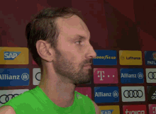 a man in a green tank top is laughing with another man in a red adidas jacket