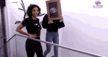 a woman is holding a picture frame in front of her face while standing on a staircase .