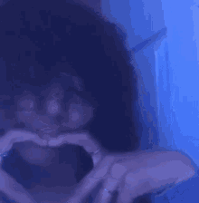 a woman with curly hair is making a funny face in front of a blue wall .
