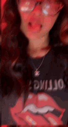 a girl wearing glasses and a rolling stones shirt is making a face .