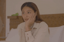 a woman is sitting on a bed with her hand on her face