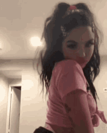 a girl in a pink shirt and black shorts is standing in a room .
