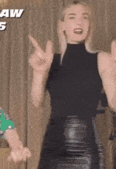 a woman in a black tank top and a black leather skirt is dancing in a room .