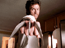 a man in a white shirt is holding a pair of claws in his fist