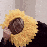 a person wearing a yellow sunflower hat on their head .