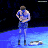 a man without a shirt is standing on a blue mat with josephquinngifs above him