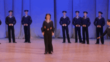 a group of men in sailor uniforms are standing in a line on a stage