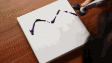 a person is using a brush to spread purple paint on a white surface