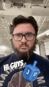 a man with glasses and a beard is holding a blue menorah in his hand .