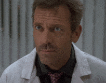 a close up of a man wearing a white coat and a pink tie