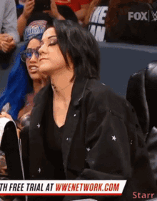 a woman is sitting in a stadium watching a free trial at wwenetwork.com
