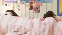 two girls laying under a striped blanket with one wearing a headband that says ' i love you ' on it