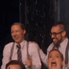 a group of people are standing next to each other on a stage laughing .