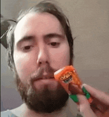a man with a beard is eating a cheetos bar .
