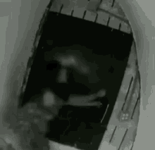a black and white photo of a person looking out of a window .
