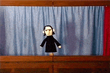 a puppet with headphones is standing in front of a curtain