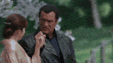 a man in a black leather jacket holds a woman 's hand in a park
