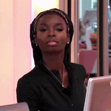 a woman wearing a head scarf and a necklace is sitting in front of a computer