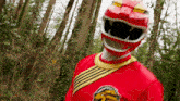 a red power ranger stands in the woods