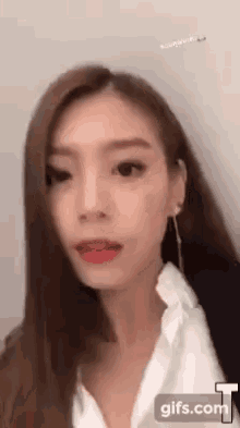 a close up of a woman 's face with long hair and a white shirt .
