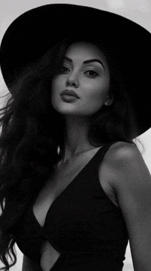 a black and white photo of a woman wearing a hat and a black tank top