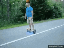 a man in a blue shirt is riding a hoverboard on a road