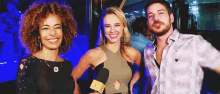 a man and two women are posing for a picture with one woman holding a microphone that says ' ntv '