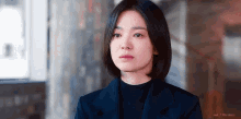 the woman is wearing a black turtleneck and a black jacket .