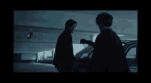two men are standing next to each other in a parking garage