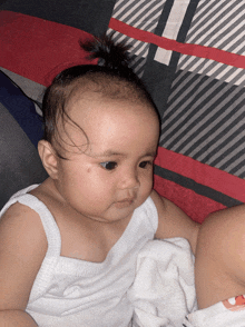 a baby in a white tank top is sitting on a bed
