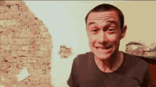 a man is making a face in front of a brick wall .