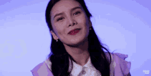 a woman wearing a purple jacket and white shirt is smiling and looking at the camera .