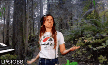 a woman wearing headphones and a shirt that says lpgiobbi is standing in the woods