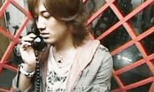 a young man is talking on a telephone in front of a wall with red squares .
